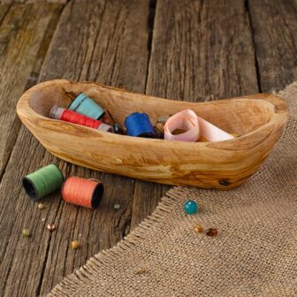 A wooden bowl filled with spools of thread.