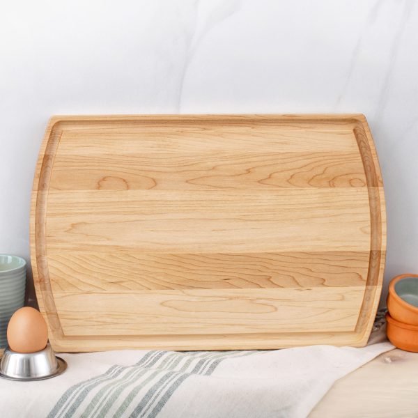 A wooden cutting board with eggs and utensils on it.