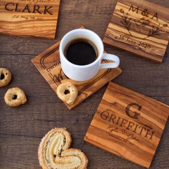 Personalized wooden coasters with a cup of coffee and cookies.