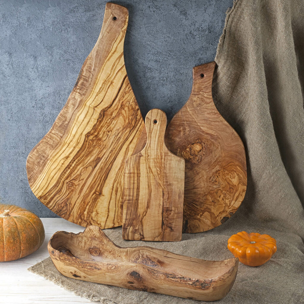 Three wooden cutting boards and a pumpkin on a table.