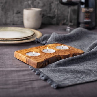 A wooden tray with two candles on it.