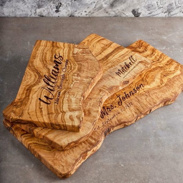 Three Live Edge Olive Wood Boards with Personalization laying on top of kitchen counter.