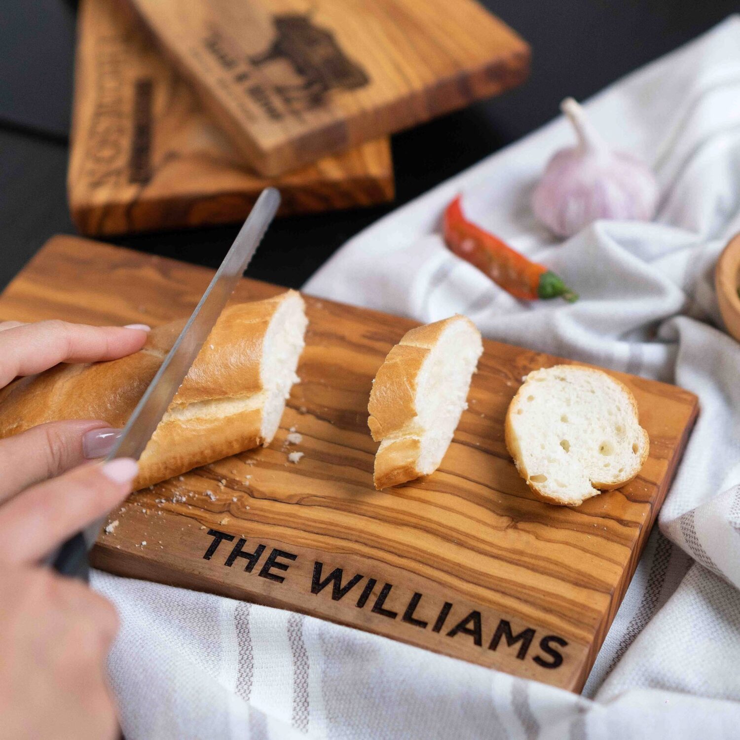 A person cutting bread on a wooden cutting board.