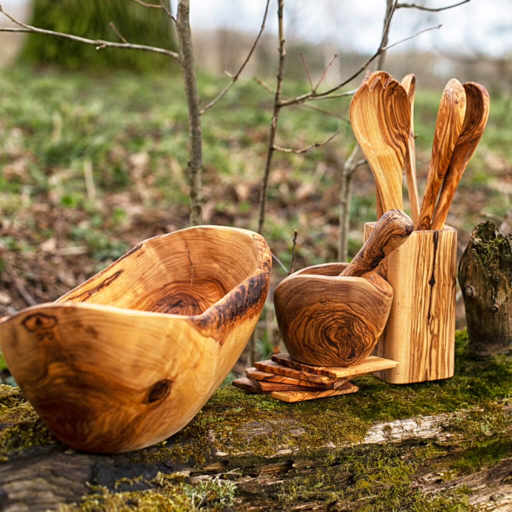 A set of wooden spoons and utensils on a tree stump.
