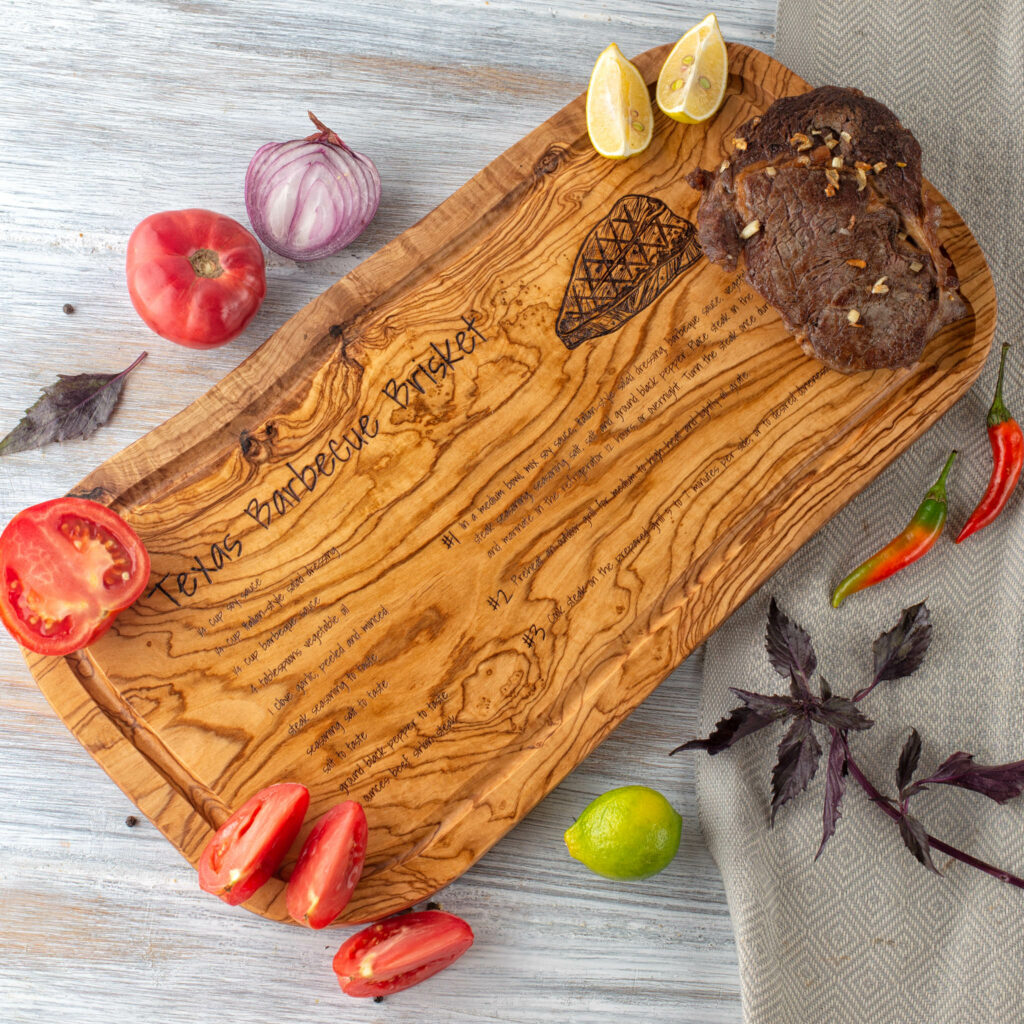 A wooden Steak Cutting Board with meat and vegetables on it.