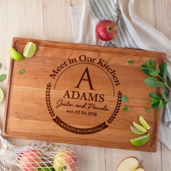 A wooden cutting board with the words'meet in our kitchen adams'.