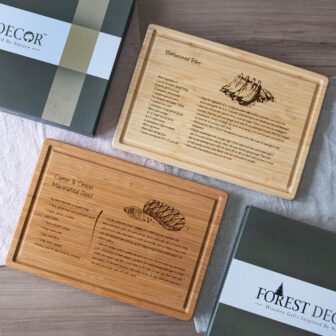 Bamboo cutting boards with engraved recipes for marinated beef and breaded fish, presented alongside their packaging.