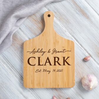 A personalized wooden cutting board engraved with the names 