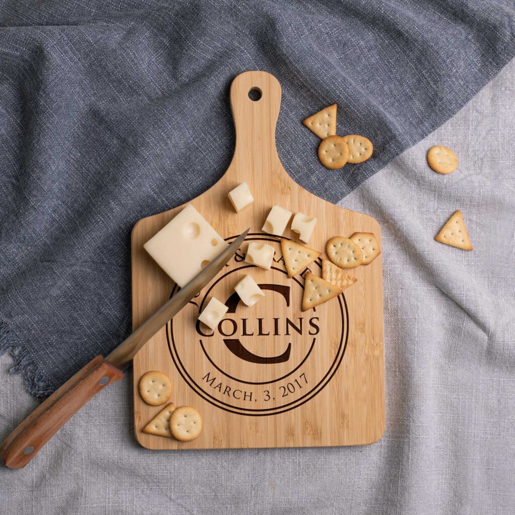 A cheese board with cubes of cheese, crackers, and a knife, personalized with the name "collins" and the date "march 3, 2017".