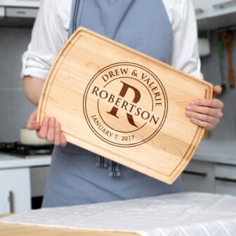 A woman is holding up a Personalized Monogram Cutting Board with her name on it.