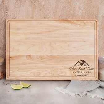 A wooden cutting board with an image of mountains and a lime next to it.