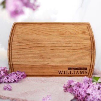 A wooden cutting board with purple flowers.