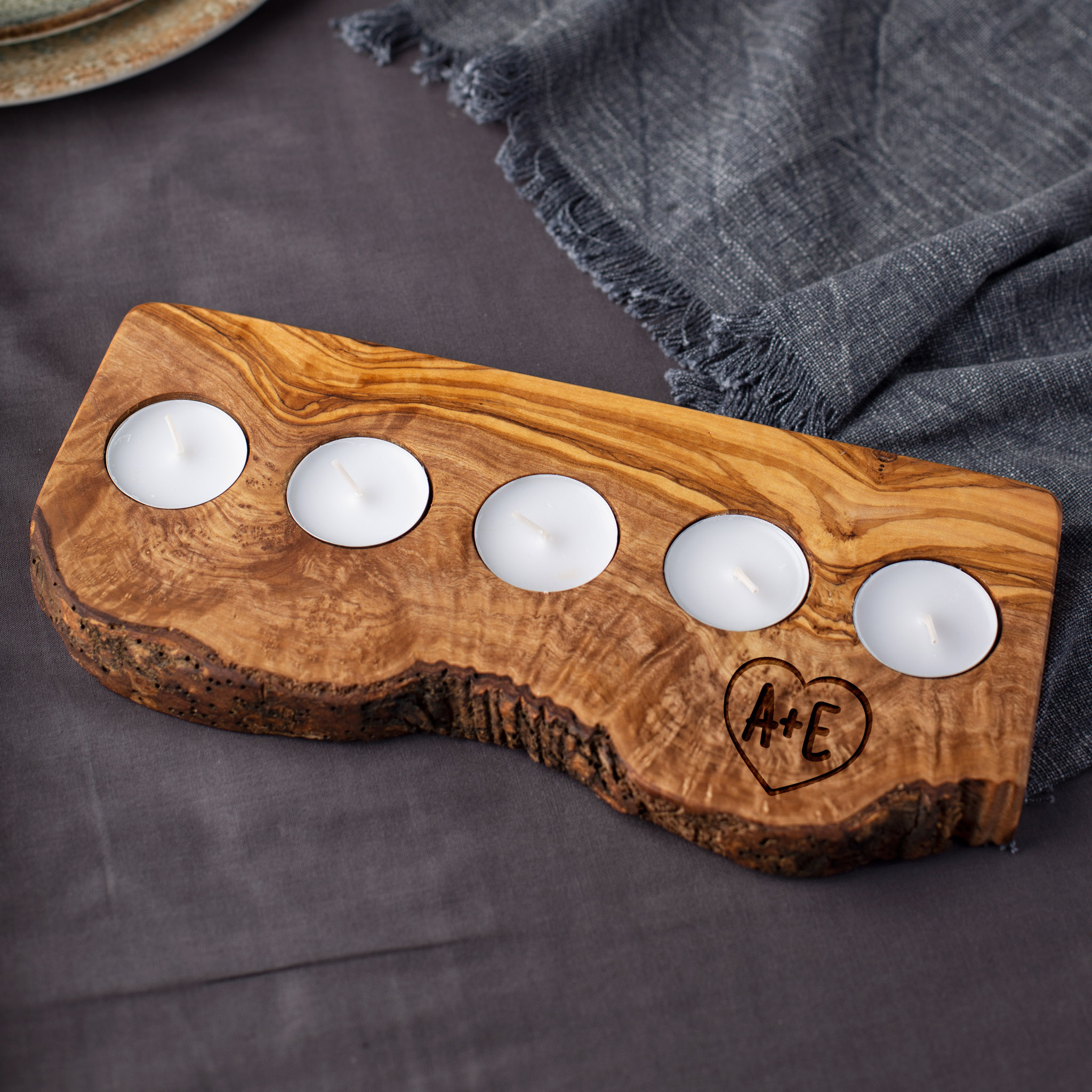A wooden tealight candle holder with four candles on it.