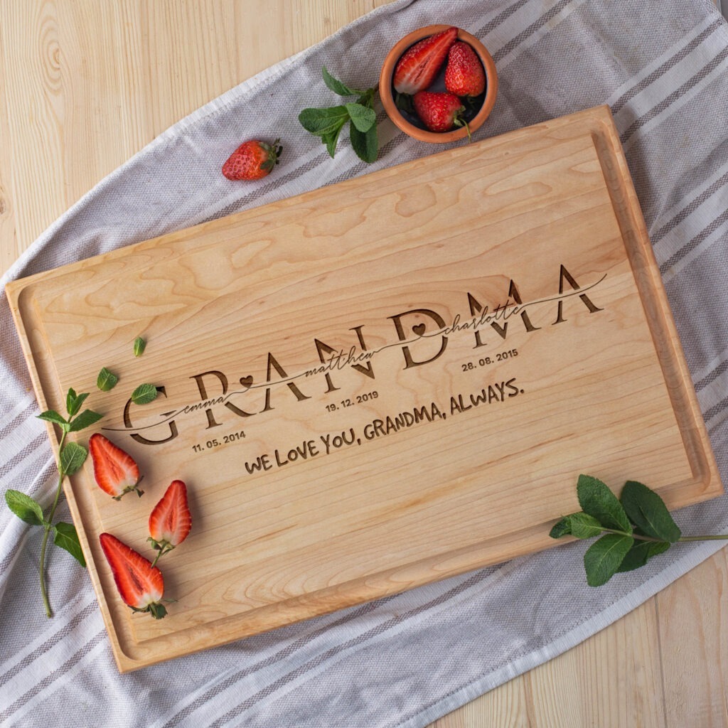 Custom-engraved wooden tray with the word "grandma" and dates, accompanied by strawberries and green leaves, creates a sentimental keepsake.