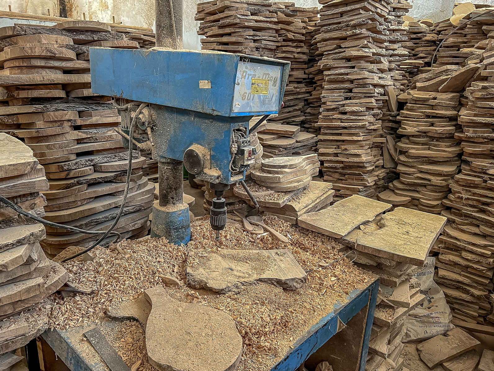 A machine in a room full of piles of wood.