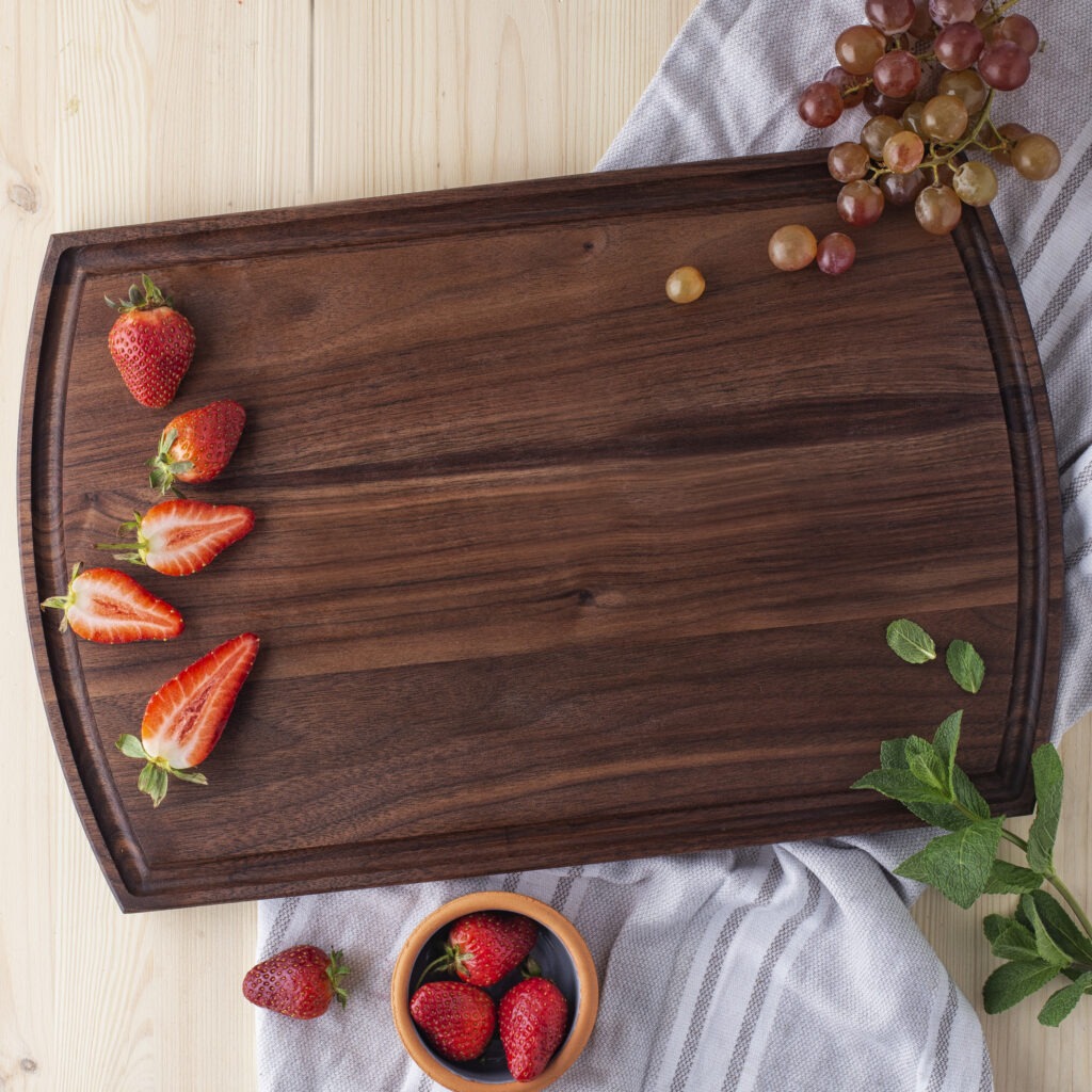 A cutting board juice groove with strawberries and grapes.