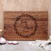 A wooden cutting board with the name of the bride and groom on it.