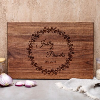 A wooden cutting board with the name of the bride and groom on it.