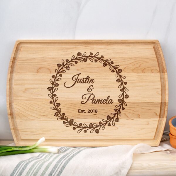 A wooden cutting board with the name of the bride and groom on it.