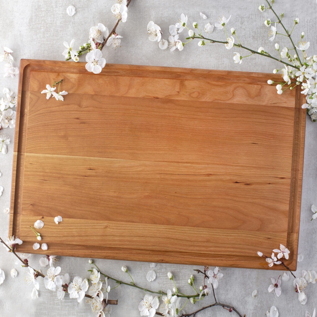 A Large Wood Cutting Board with Juice Groove with cherry blossoms on it.