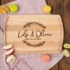 A wooden cutting board with the words lily and olivia.