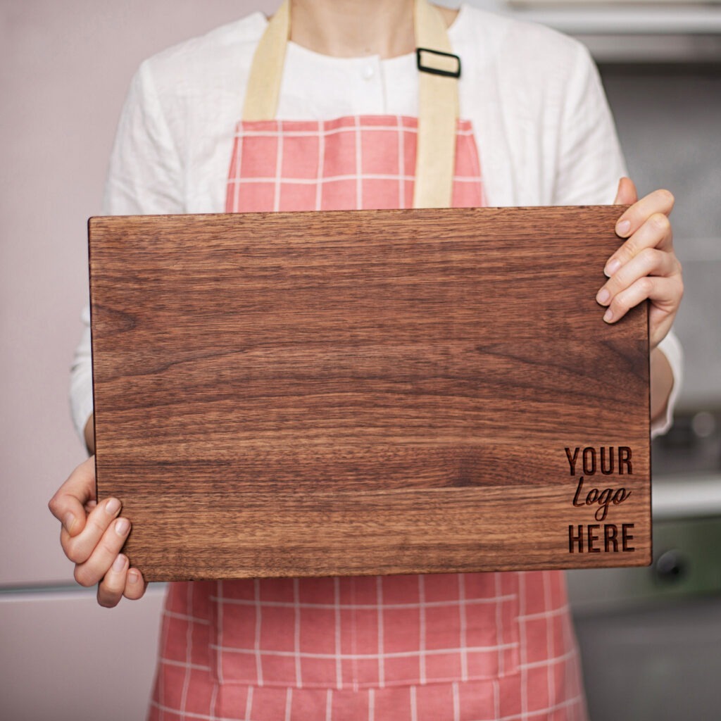 Person in an apron holding a wooden cutting board with a placeholder text for a logo.