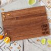 A wooden Custom Logo Cutting Board with oranges and almonds on it.