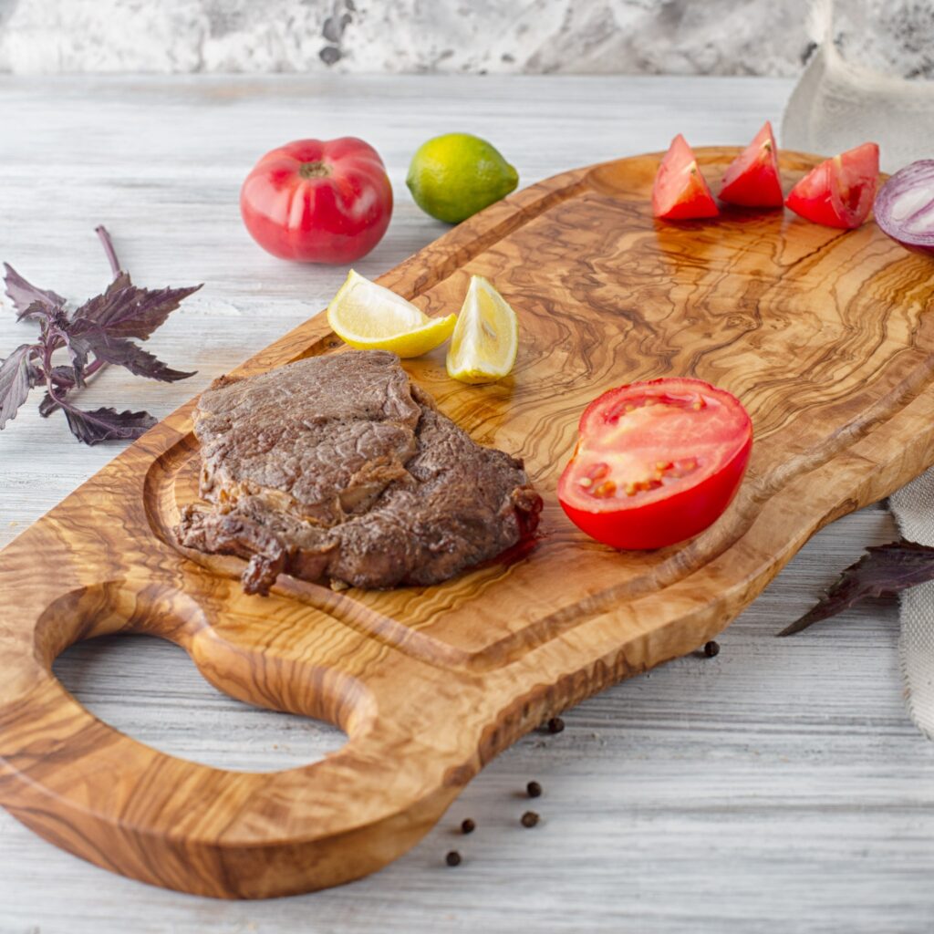 An Olive Wood Board with a steak on it.