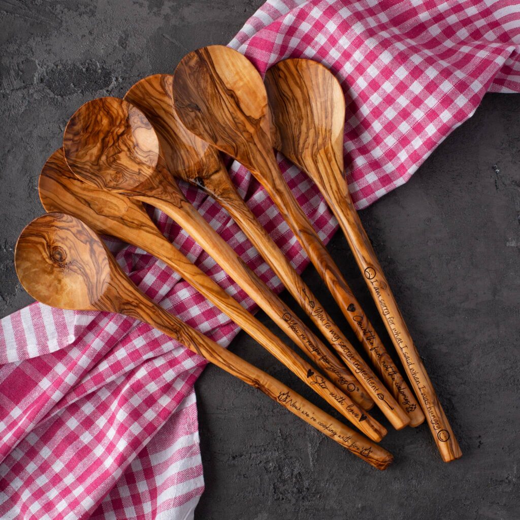 Olive wood spoons on a pink checkered cloth.