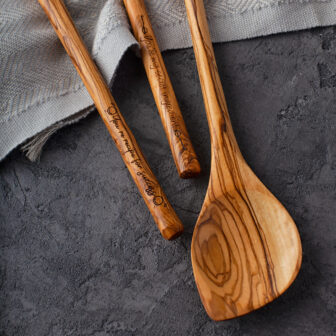 Three wooden spoons on a grey background.