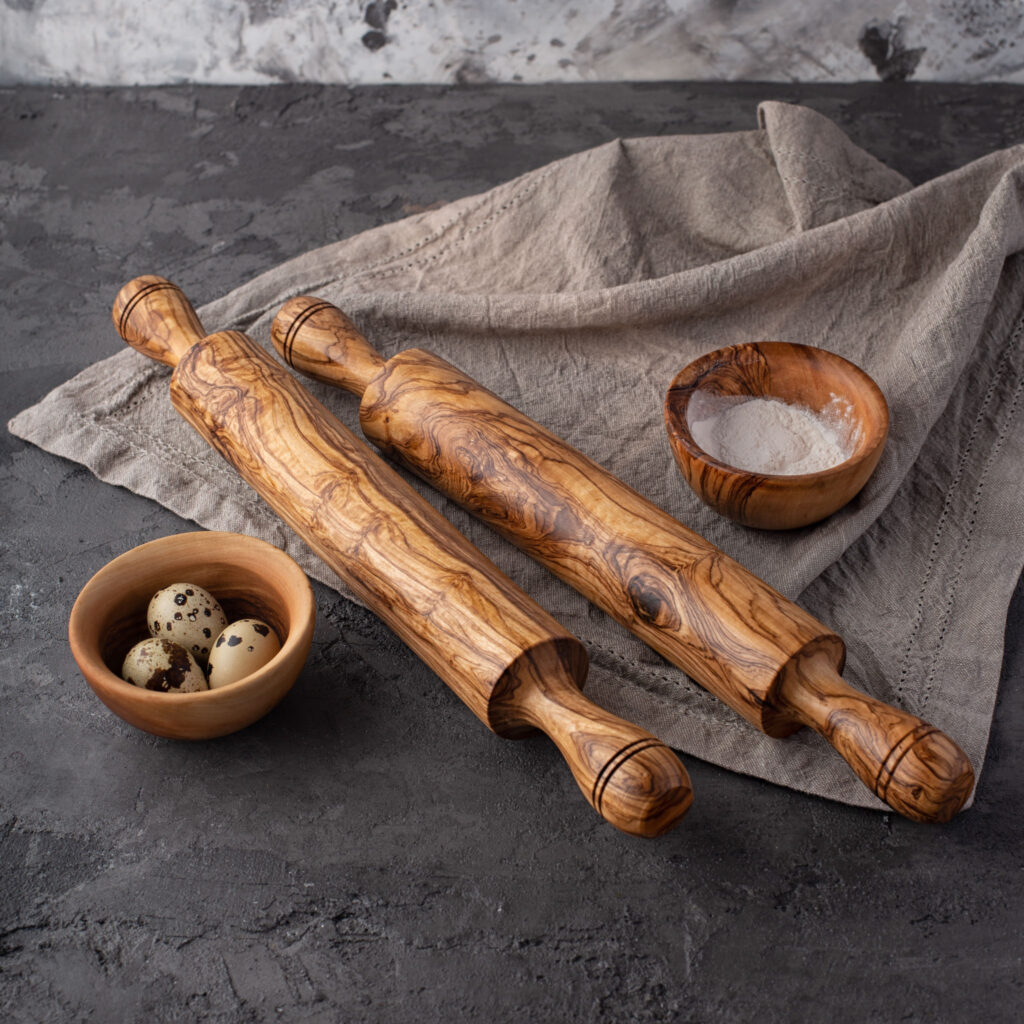 Two wooden rolling pins and a bowl of eggs.