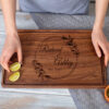 A woman is holding a wooden cutting board with a lime on it.