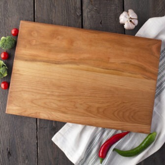A Wood Cutting Board (Cherry) with vegetables and peppers on it.