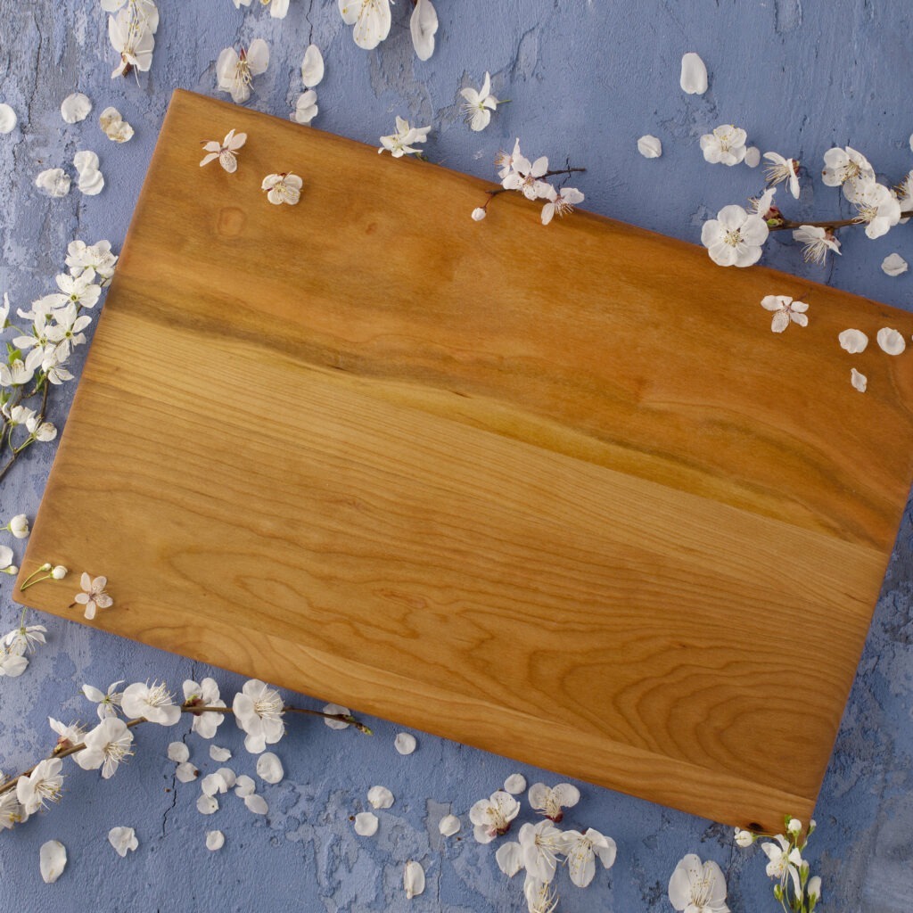 A wood cheese board with cherry blossoms on it.