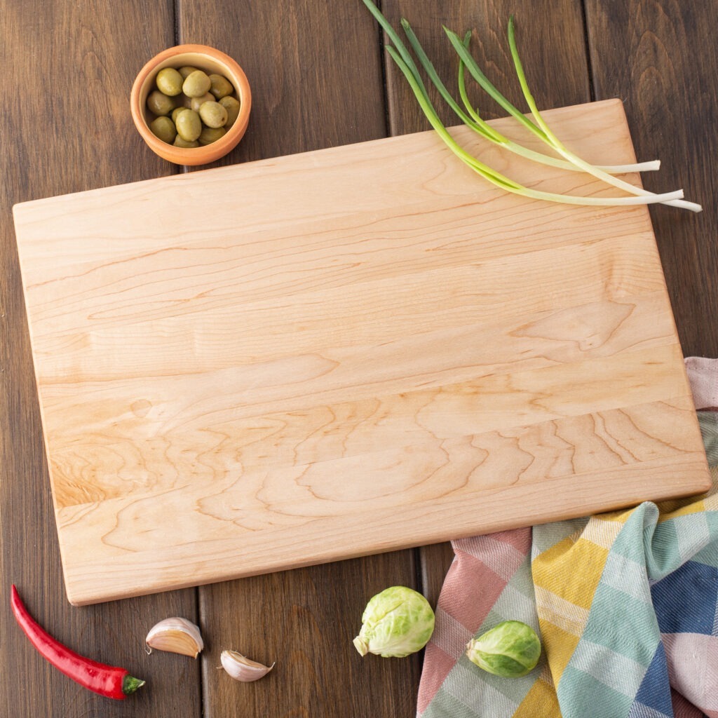 A wood meat cutting board with vegetables on it.