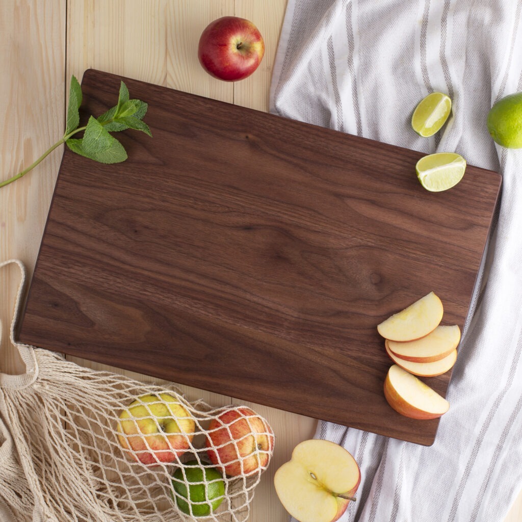 A Wood Cutting Board (Walnut) with apples and a bag of apples.