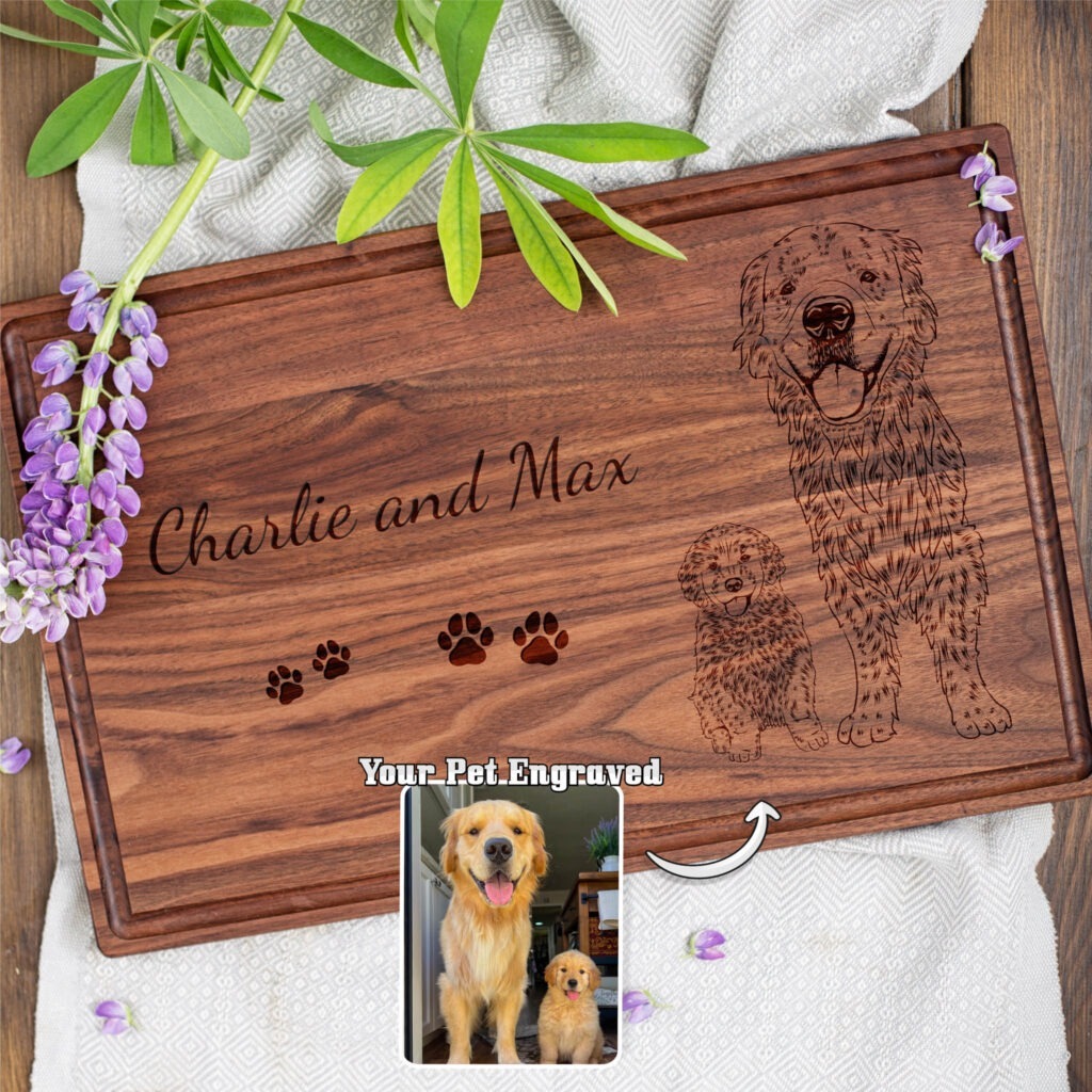 A personalized wooden cutting board engraved with the image of a dog and a puppy, named charlie and max, with decorative floral elements around.