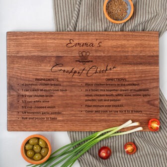 A recipe for "emma's crockpot chicken" written on a wooden cutting board, surrounded by ingredients.