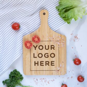 Wooden cutting board with text "your logo here" surrounded by fresh vegetables on a striped kitchen towel.