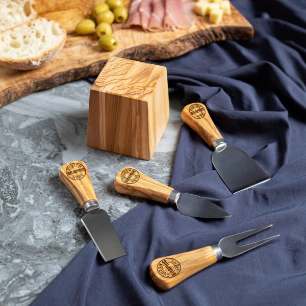 Logo-engraved cheese knives beside a magnetic olive wood stand