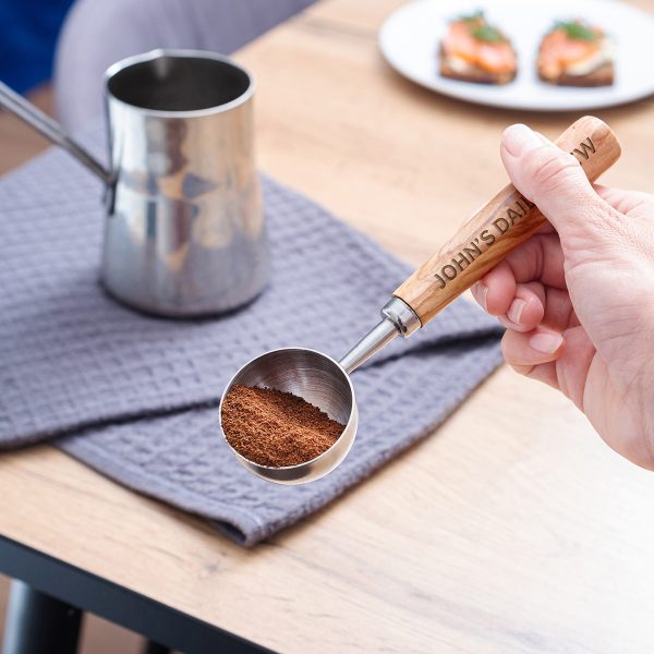 Engraved coffee scoop filled with ground coffee