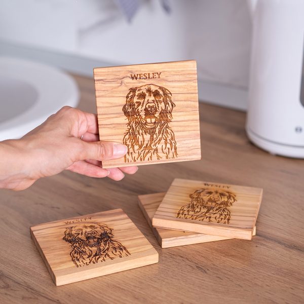 Hand holding an olive wood coaster engraved with a dog portrait