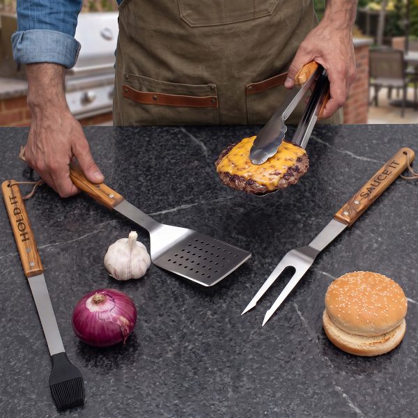 Engraved olive wood grill tools at an outdoor barbecue