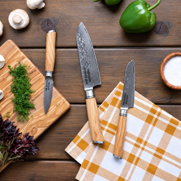 Three engraved Damascus knives on a kitchen table