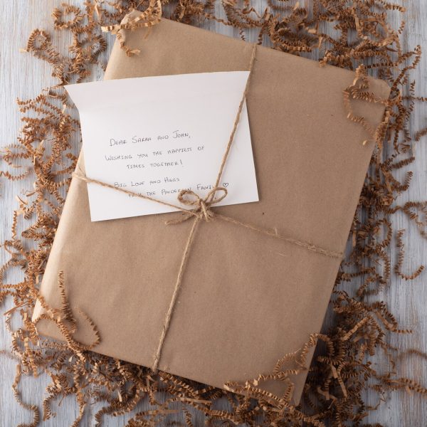 A gift wrapped in brown paper with a note inside.