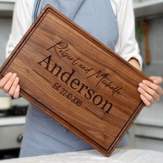 A woman is holding up an Engraved Cutting Board with the name Anderson.