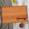 A wooden cutting board with a key on it.