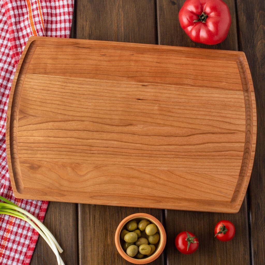 A rustic cutting board with olives and tomatoes on it.