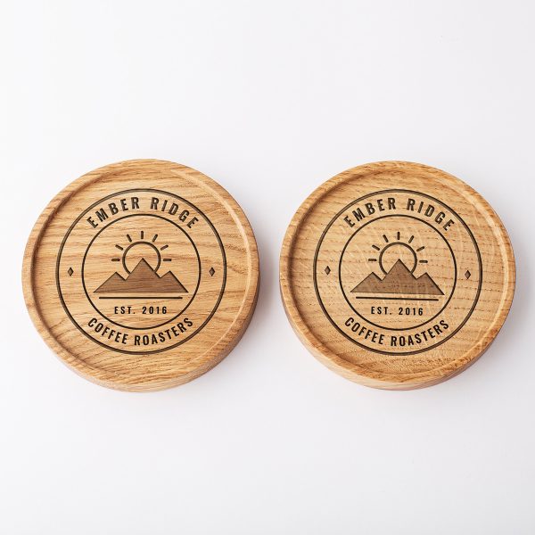 Two round oak coasters engraved with the same logo