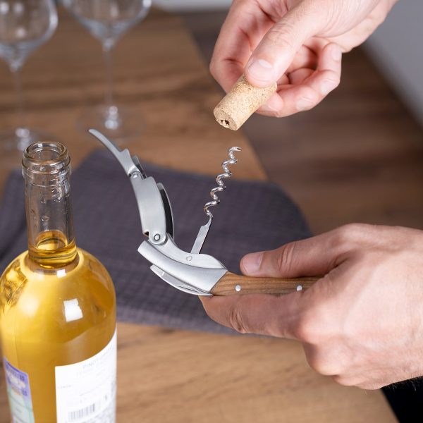 Olive wood waiter's corkscrew pulling a cork from a wine bottle